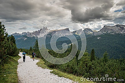 Climbers walking down a road in a Dolomite mountain landscape after a hard climb Stock Photo