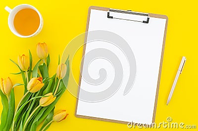 Clipboard mockup. Blank cliboard on yellow background with flowers, cup of tea and golden pen. Wedding. Birthday. Happy Stock Photo