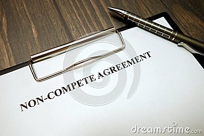 Clipboard with non-compete agreement and pen on desk Stock Photo