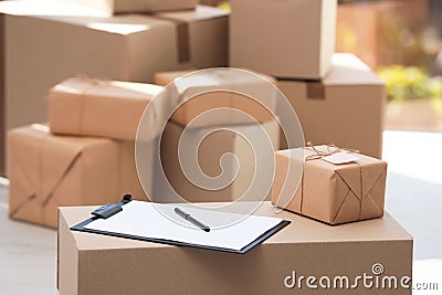 Clipboard, parcel with tag and blurred stacked boxes on background Stock Photo