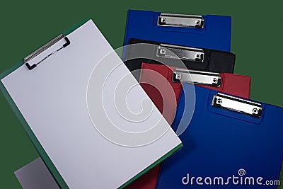 Clipboards, many pieces, assorted colors, clip paper, ready to use, dark green background on the back Stock Photo