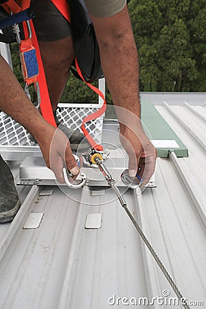 Clipping industrial Karabiner connected with fall arrest shock absorbing safety lanyard device into horizontal lifeline Stock Photo