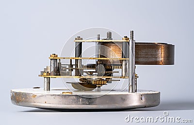 Clock lying on dial with open clockwork on an isolated gray studio background. Clockwork mechanism with gears, cogwheel Stock Photo