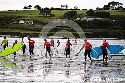 Clonakilty, Ireland - students from a local surfing school take their boards into the water at Inchydoney beach Editorial Stock Photo