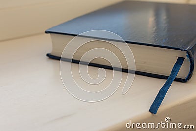 Close blue book with book marker on white wooden table. Education and learning concept. Science background. Stock Photo