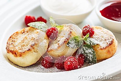 Close cheese pancakes, syrniki, curd fritters with fresh raspberries on white plate background Stock Photo