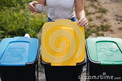 Close of female throwing out in recycling bin clean empty plastic container. Different colour of recycling bins. Front Stock Photo