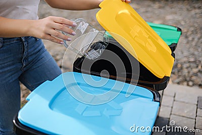 Close of female throwing out in recycling bin clean empty plastic container. Different colour of recycling bins Stock Photo