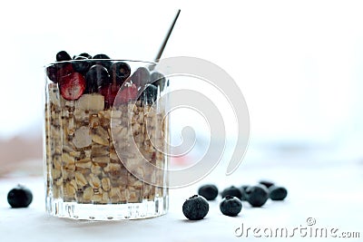 Close glass of granola oatmeal with chia, cranberry and american blueberries on table Stock Photo