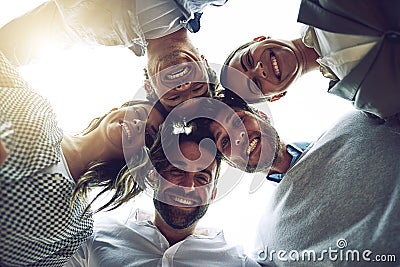 We are a close group of friends. Low angle portrait of a group of cheerful young work colleagues standing in a circle Stock Photo