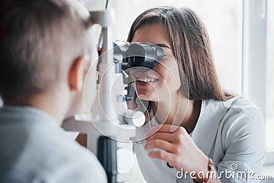 Close look. Little boy having test for his eyes with special optical apparatus by female doctor Stock Photo