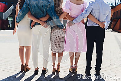 Close male and female friends walking down city street together. Rear view of mix raced people walking outside and Stock Photo