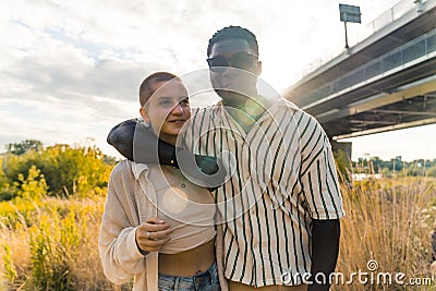 Close mixed race friendship. Young happy African man and caucasian woman hugging and smiling, enjoying a sunny summer Stock Photo