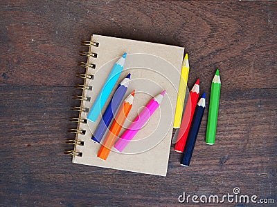 Close note book and color pencil on wooden background Stock Photo