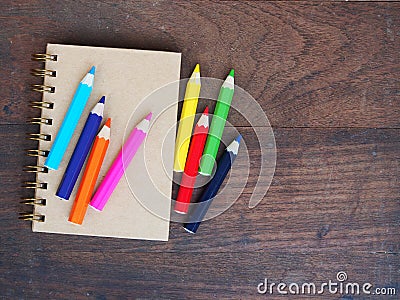 Close note book and color pencil on wooden background Stock Photo