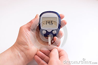 Close person checking blood sugar with glucometer and test strip at home Stock Photo