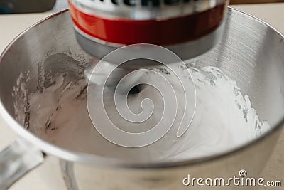 Hand of a young woman who is demonstrating meringue on the mixer whisk near bowl Stock Photo