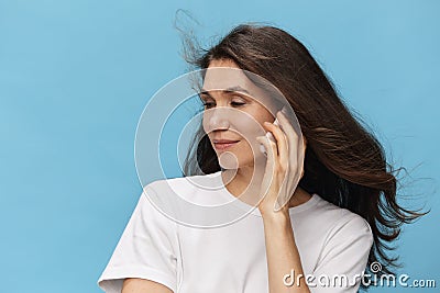 a close portrait of a beautiful depressed brunette woman with hair blowing in the wind during a telephone conversation Stock Photo