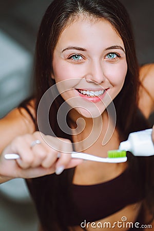 Close is portrait of young woman holding toothpaste and a toothbrush. Feemale look into camera and smile with a snow Stock Photo