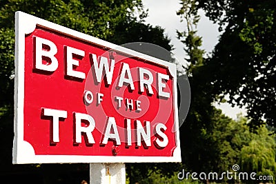 Close up of railway sign reading BEWARE OF THE TRAINS. Stock Photo
