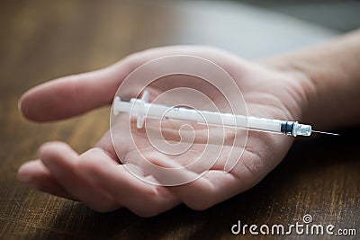 Close up of addict hand and used drug syringe Stock Photo