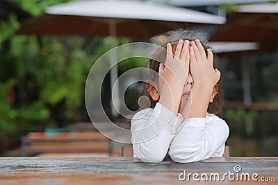 Close-up of adorable little Asian child girl expressed disappointment or displeasure on the wood table Stock Photo