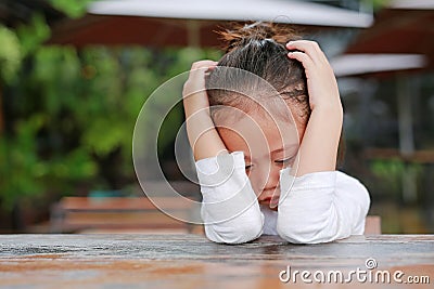 Close-up of adorable little Asian child girl expressed disappointment or displeasure on the wood table Stock Photo