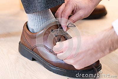 Close Up Of Adult Son Helping Senior Man Tie Shoelaces Stock Photo