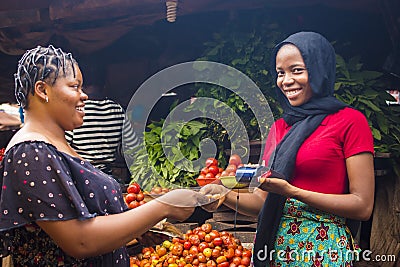 Close up of an african woman selling food stuff in a local african market holding a mobile point of sale device collecting a Stock Photo