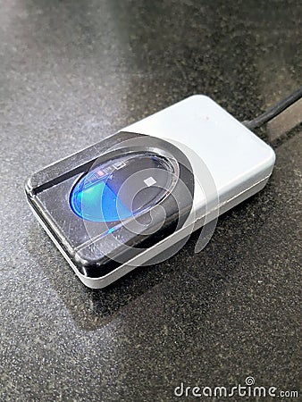 A close-up, angled view of a Fingerprint Reader, placed on a dark, textured surface Stock Photo