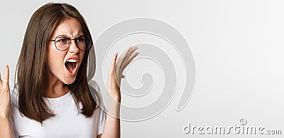 Close-up of angry and outraged beautiful woman in glasses yelling and shaking hands, having an argument Stock Photo