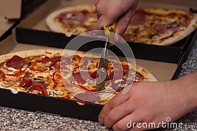 Close up of anonimous pizza chef slicing appetising pizza Stock Photo