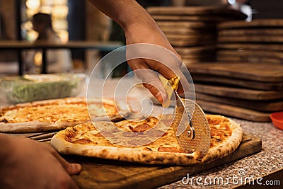 Close up of anonimous pizza chef slicing appetising pizza Stock Photo