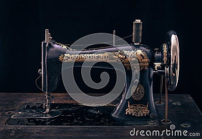 Close up of antique sewing machine Singer on black background. Editorial Stock Photo