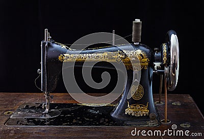 Close up of antique sewing machine Singer on black background. Editorial Stock Photo