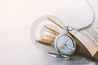 Close up of antique silver pocket watch and opened book Stock Photo