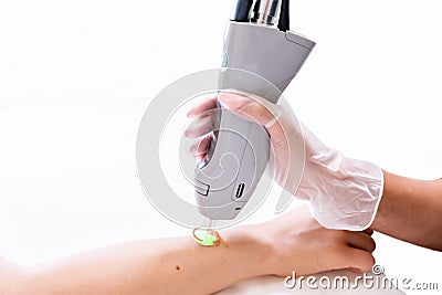 Close up of arm laser hair removal session with beauty technician and female patient, epilating after shaving, in a cosmetology Stock Photo