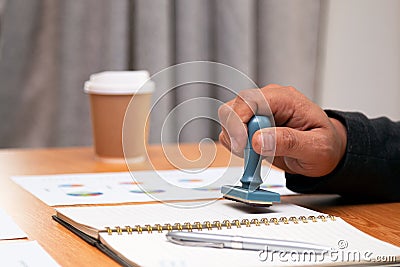 Close up Asian businessman holding rubber stamp and stamping with approved stamp Stock Photo
