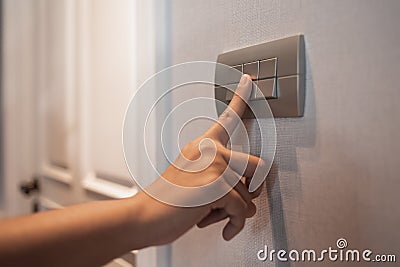 Asian female right hand is turning off on grey light switch Stock Photo