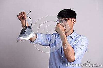Close up asian man holding dirty stinky shoe with an expression of disgust. Healthcare concept Stock Photo