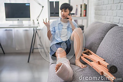 Close-up Of Asian people Broken Leg And Crutches. She explains and talks on the phone and recovers at home Stock Photo