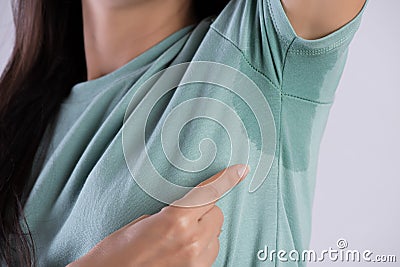 Close-up asian woman with hyperhidrosis sweating. Young asia woman with sweat stain on her clothes against grey background. Stock Photo