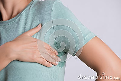 Close-up asian woman with hyperhidrosis sweating. Young asia woman with sweat stain on her clothes against grey background. Stock Photo