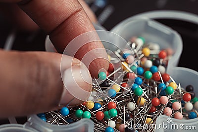 close up of assortment of colorful sewing pins hand reaching Stock Photo
