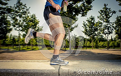 Close up athletic legs of young man running in city park with trees on summer training session practicing sport healthy lifestyle Stock Photo