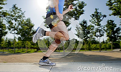 Close up athletic legs of young man running in city park with trees on summer training session practicing sport healthy lifestyle Stock Photo