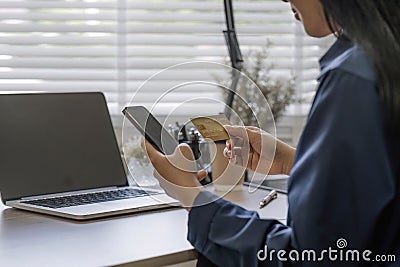 Close up attractive millennia Asian female holding her smartphone and credit card, using mobile banking app or online Stock Photo
