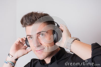 Close up of an attractive young man in black listening to a podcast while smiling Stock Photo