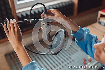 Close-up of audio engineer working in sound record studio, using microphone, mixing board, software to create new song Stock Photo