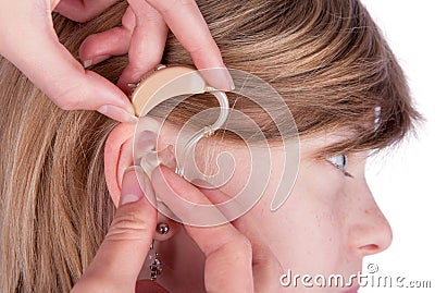 Close up of an Audiologist hands inserting a hearing aid into ea Stock Photo